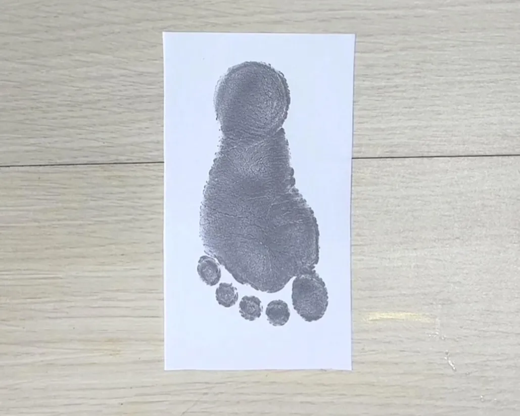 画用紙に子どもの足形をとっている画像