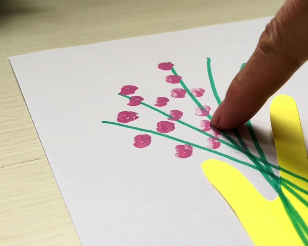 指に絵の具をつけ、茎の先にスタンプをしている様子
