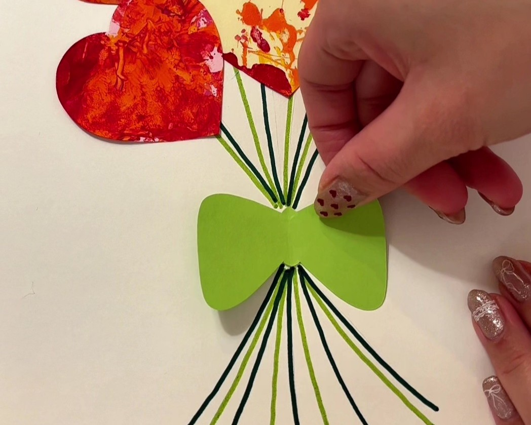 茎の結び目あたりに、画用紙で作ったリボンを貼っている様子