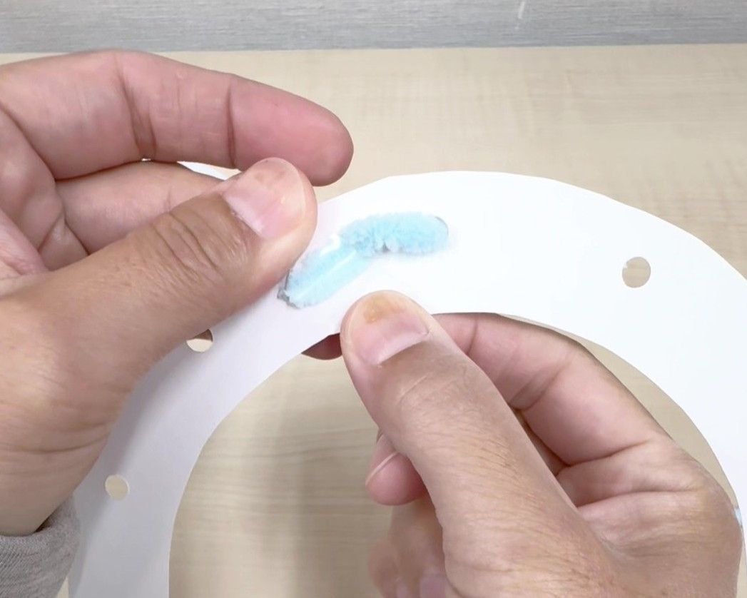 毛糸を穴に通し端をセロハンテープで固定している画像