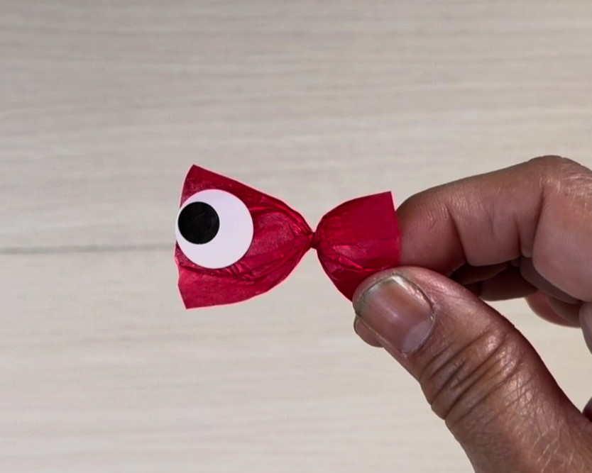 ねじった赤い花紙にシールで目を貼り、金魚に見立てた画像