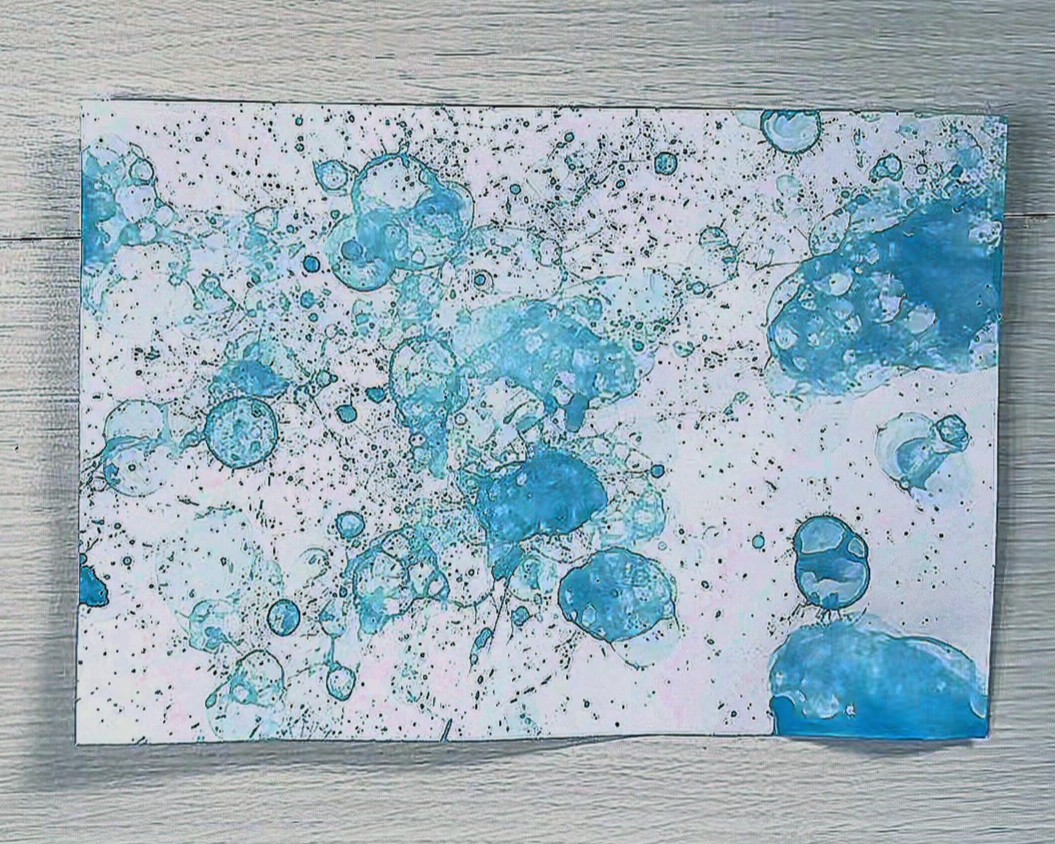 白い画用紙に水色の絵の具を吹きかけた画像