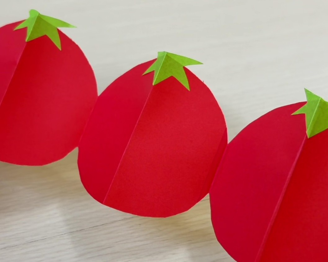 トマトの形に切った折り紙に折り紙で作ったヘタを貼った様子